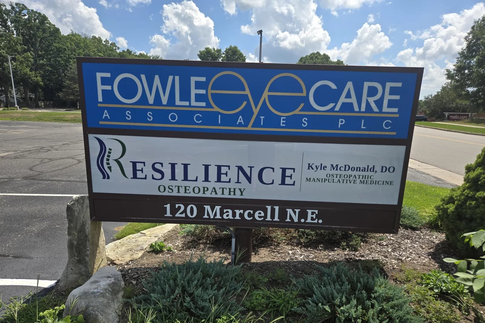 The roadside sign at 120 Marcell Drive NE. The Resilience Osteopathy panel, with Dr. Kyle McDonald's name and Osteopathic Manipulative Medicine beside it, sits below the Fowle EyeCare panel, and the street number is on the base of the sign.
